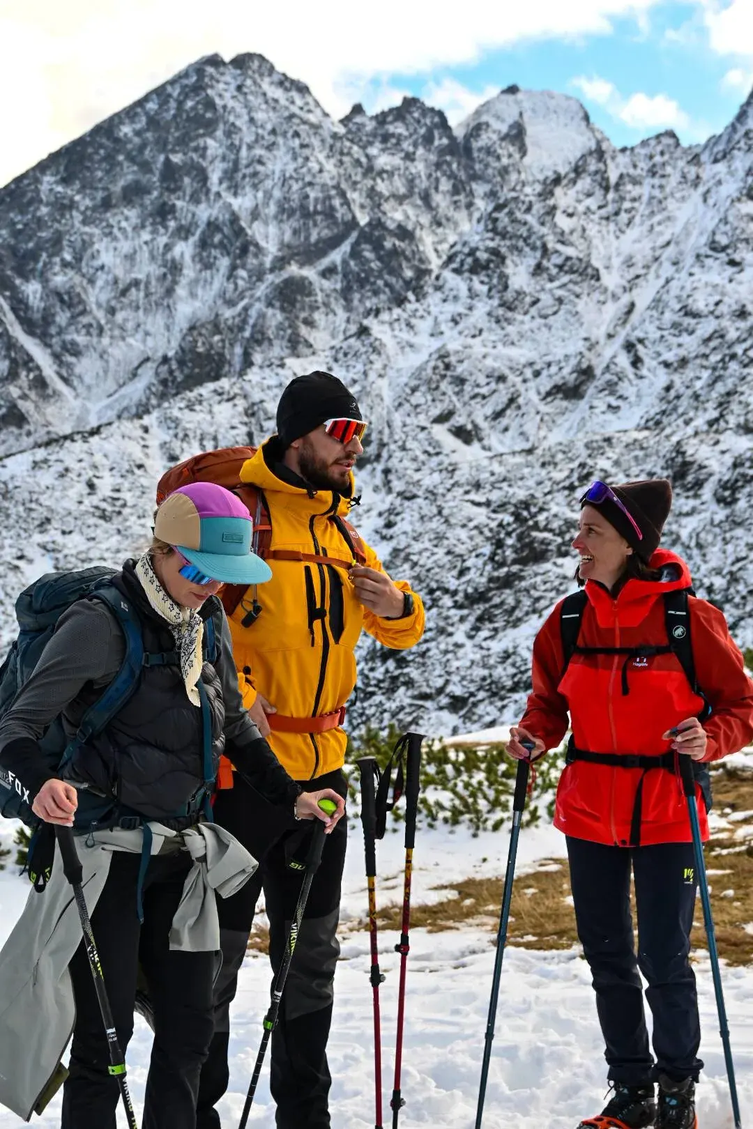 Trzyosobowa grupa z kijami trekkingowymi na zimowym szlaku w Tatrach